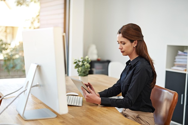 La tecnología es una parte integral de los negocios modernos Fotografía de una joven empresaria usando una tableta digital en el trabajo