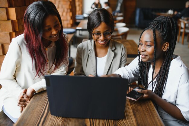 La tecnología es un recurso fantástico para las herramientas de estudio Tres estudiantes en el café