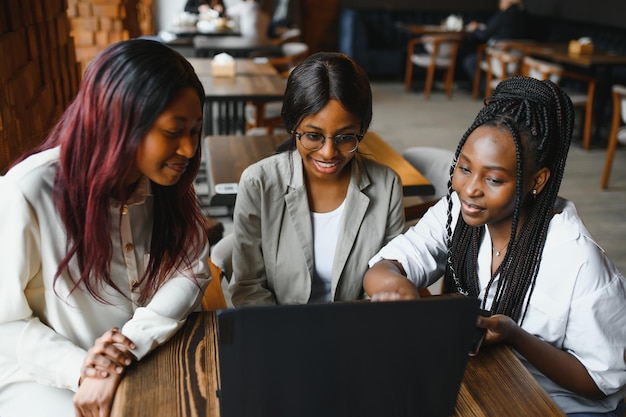 La tecnología es un recurso fantástico para las herramientas de estudio Tres estudiantes en el café