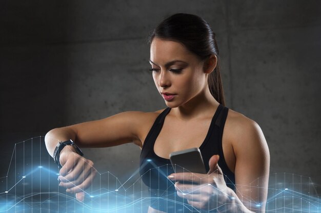 Foto tecnología de fitness deportivo y concepto de personas mujer joven con reloj de ritmo cardíaco y teléfono inteligente en el gimnasio