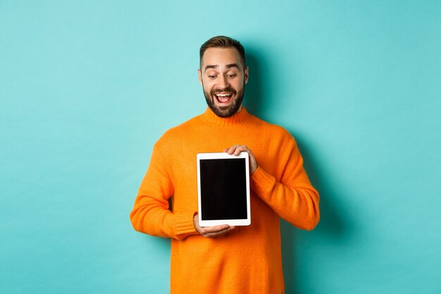 Tecnología. Hombre adulto alegre mirando y mostrando la pantalla de la tableta digital, de pie