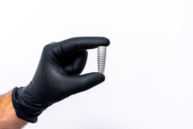 Tecnología de implantes dentales aislados en blanco en la mano del dentista. Guantes de látex negros.