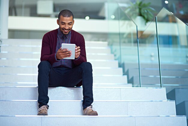 La tecnología impulsa la innovación Foto de un joven hombre de negocios que usa una tableta digital en las escaleras de una oficina moderna