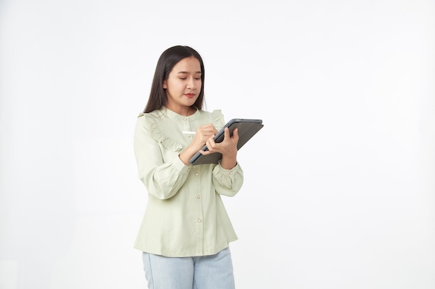 Tecnología inalámbrica. Hermosa joven asiática sosteniendo tableta digital y mirando a la cámara con una sonrisa mientras está de pie aislado sobre fondo blanco.