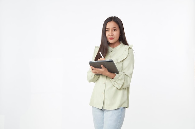 Tecnología inalámbrica. Hermosa joven asiática sosteniendo tableta digital y mirando a la cámara con una sonrisa mientras está de pie aislado sobre fondo blanco.