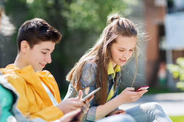 tecnología, internet y concepto de personas - adolescente feliz con computadora de tablet pc y niña con teléfono inteligente al aire libre