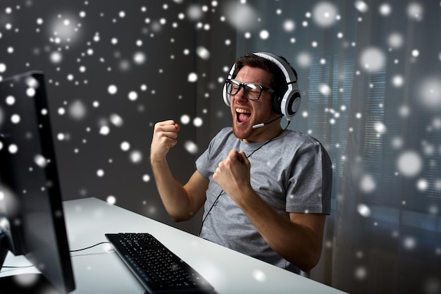 tecnología, juegos, entretenimiento, juguemos y el concepto de la gente: joven con anteojos con auriculares jugando y ganando juegos de computadora y transmisión de reproducción o video de recorrido sobre la nieve