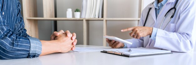 Tecnología en medicina y cuidado de la salud, consulta con el médico Discutir registros con el paciente mediante el uso de una tableta digital en el consultorio