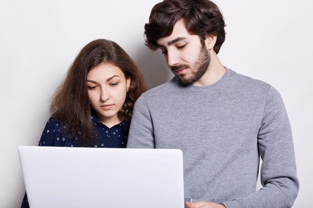 Tecnología moderna y concepto de comunicación. Un hombre barbudo elegante y una mujer bonita viendo video