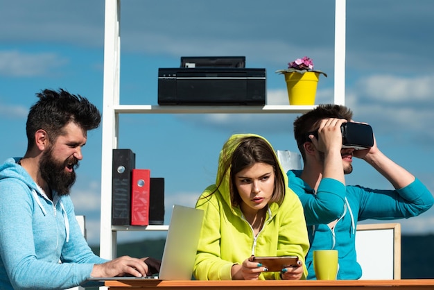 Tecnología moderna Hombres y mujeres jóvenes sentados en una mesa con gafas de realidad virtual Equipo de negocios probando auriculares de realidad virtual en una oficina al aire libre Negocio virtual