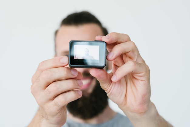Tecnologia moderna para criação de conteúdo de vídeo homem segurando câmera de ação e gravando-se equipamentos e ferramentas de blogueiro