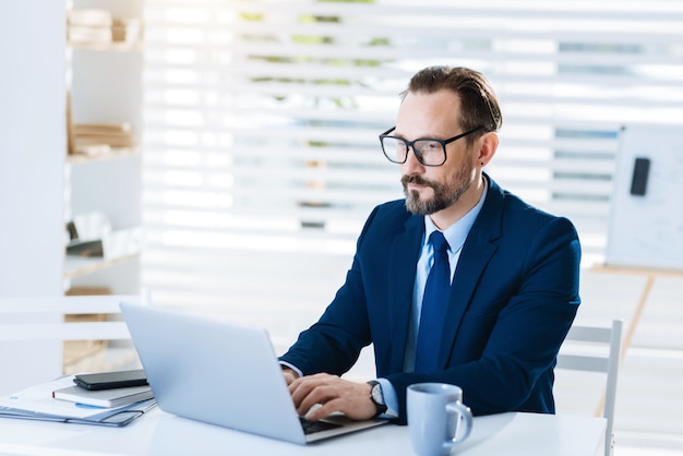 Tecnologia moderna. Resposta de digitação de empresário atraente e profissional enquanto está sentado e olhando para a tela