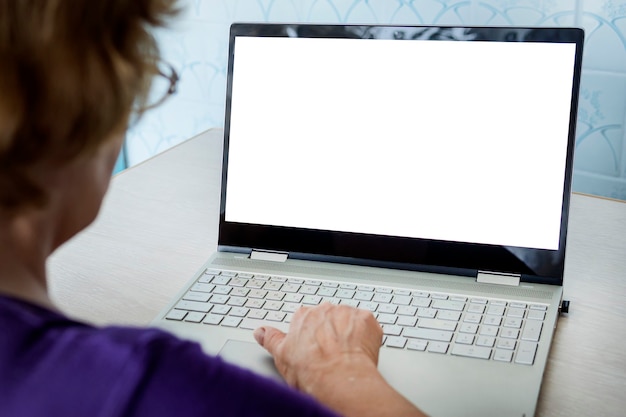 Foto tecnología moderna y vejez. abuela en contacto en línea. mujer madura alegre que muestra la pantalla en blanco en la computadora portátil, espacio vacío para prueba y diseño.