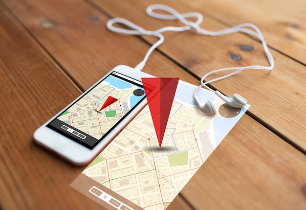 Foto tecnología, navegación, gadget y concepto de objeto - cierre de smartphone blanco y auriculares en superficie de madera con mapa de navegador gps en pantalla