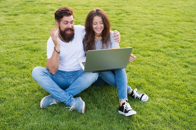 Tecnología en el ocio Pareja enamorada usa laptop sobre hierba verde Nueva tecnología Tecnología para la comunicación Tecnología informática Medios y redes sociales Navegación por Internet Mundo virtual Web