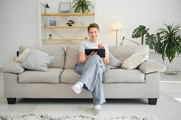 Tecnología de personas y concepto de internet feliz mujer de mediana edad con tablet pc en casa