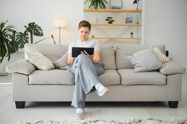 Tecnología de personas y concepto de internet feliz mujer de mediana edad con tablet pc en casa