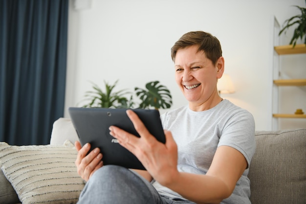 Tecnología de personas y concepto de internet feliz mujer de mediana edad con tablet pc en casa