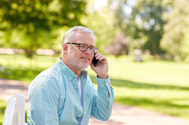 tecnología, personas mayores y concepto de comunicación - anciano feliz marcando el número de teléfono y llamando al teléfono inteligente en el parque de verano