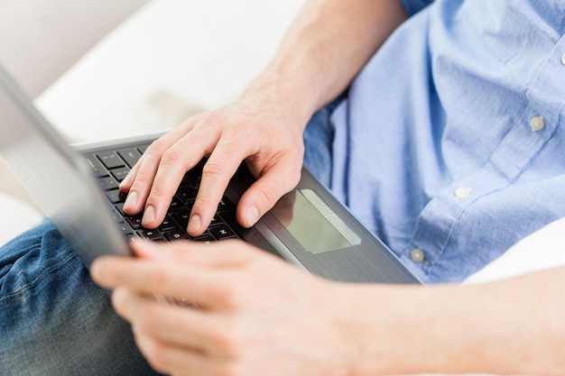 tecnologia, pessoas e conceito de estilo de vida - close-up de mãos masculinas digitando no teclado do computador portátil em casa