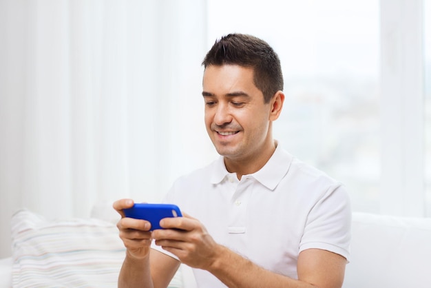 tecnologia, pessoas, estilo de vida e conceito de comunicação - homem feliz com smartphone em casa