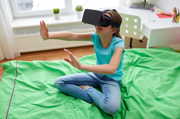 Foto tecnología, realidad aumentada, entretenimiento y concepto de personas - niña con auriculares virtuales o gafas 3d jugando en casa