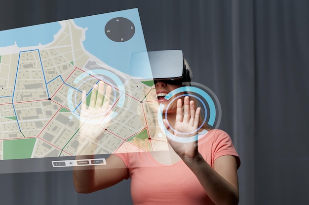 Foto tecnología, realidad virtual, ciberespacio, entretenimiento y concepto de personas - mujer joven feliz con auriculares de realidad virtual o gafas 3d en casa mirando la proyección del mapa del navegador gps