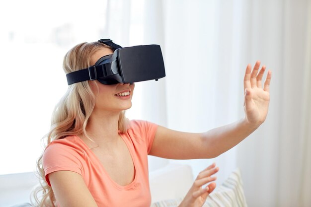 tecnología, realidad virtual, entretenimiento y concepto de personas - mujer joven feliz con auriculares de realidad virtual o gafas 3d jugando en casa y tocando algo invisible