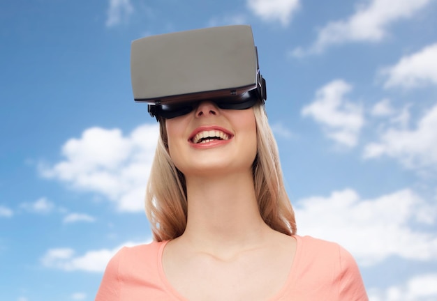 tecnologia, realidade virtual, entretenimento e conceito de pessoas - jovem feliz com fone de ouvido de realidade virtual ou óculos 3d sobre céu azul e fundo de nuvens