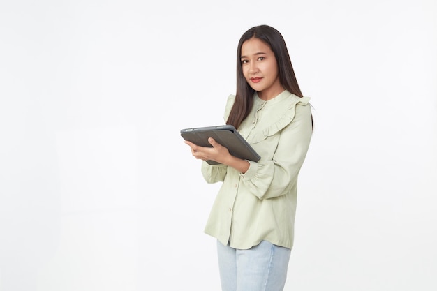 Tecnologia sem fio. Mulher jovem e bonita asiática segurando o tablet digital e olhando para a câmera com um sorriso em pé, isolado no fundo branco.