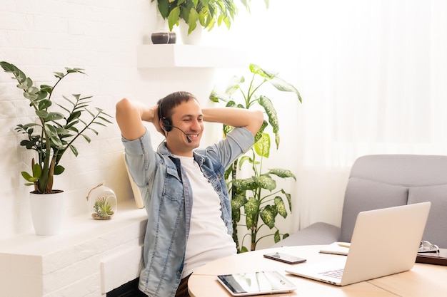 tecnología, trabajo remoto y concepto de estilo de vida - hombre feliz con anteojos con computadora portátil con chat de video y saludando con la mano en la oficina de casa