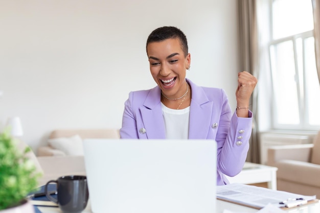 Tecnología de trabajo remoto y concepto de personas feliz sonriente joven mujer de negocios negra con computadora portátil y papeles trabajando en la oficina en casa