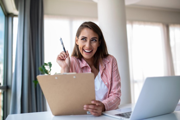 Tecnología de trabajo remoto y concepto de personas mujer de negocios joven sonriente feliz con computadora portátil y papeles que trabajan en la oficina en casa
