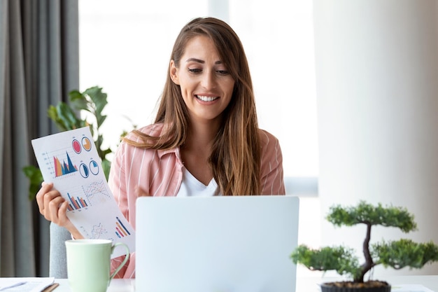 Tecnología de trabajo remoto y concepto de personas mujer de negocios joven sonriente feliz con computadora portátil y papeles que trabajan en la oficina en casa