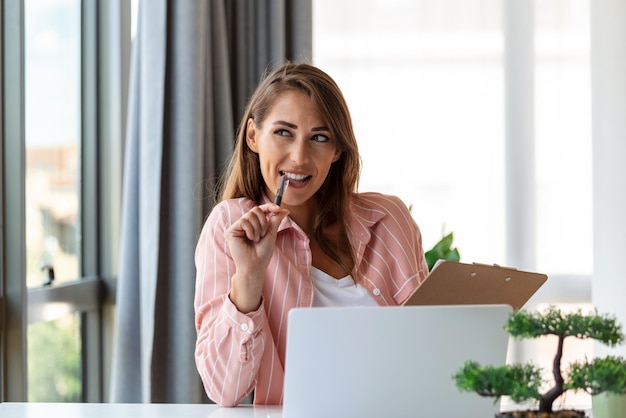 Tecnología de trabajo remoto y concepto de personas mujer de negocios joven sonriente feliz con computadora portátil y papeles que trabajan en la oficina en casa