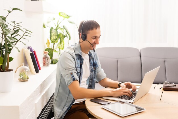 tecnologia, trabalho remoto e conceito de estilo de vida - homem feliz em óculos com computador portátil tendo chat de vídeo e acenando com a mão no escritório em casa