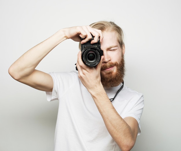 Tecnología de viajes y concepto de estilo de vida joven fotógrafo barbudo tomando fotografías con cámara digital