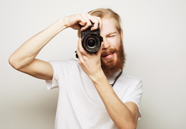 Tecnología de viajes y concepto de estilo de vida joven fotógrafo barbudo tomando fotos con cámara digital