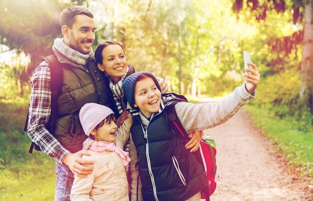 tecnología viajes turismo caminata y conceptos de personas familia feliz con mochilas tomando selfies con teléfonos inteligentes y caminatas
