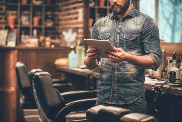 Tecnologías digitales en cualquier negocio. Primer plano, de, joven, barbudo, tenencia, tableta de digital