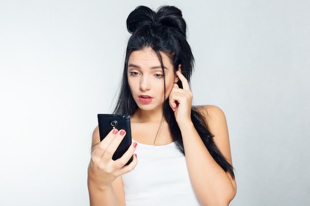 Tecnologías, emociones, estilo de vida, personas, adolescentes y concepto de selfie - Mujer pensativa con una camisa blanca en el teléfono y en el teléfono. Fondo gris aislado