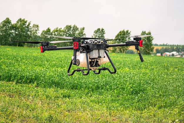Tecnologías modernas en agricultura drone industrial vuela sobre un campo verde y rocía útil