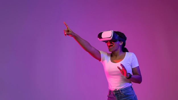Tecnologías modernas Joven mujer negra en auriculares VR disfrutando de la experiencia de realidad virtual