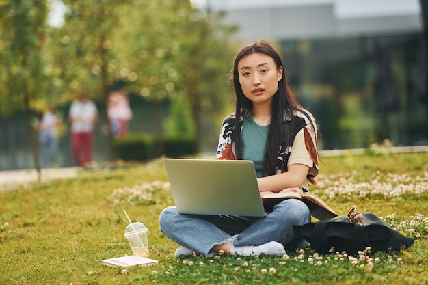 Tecnologias sem fio A jovem asiática está ao ar livre durante o dia