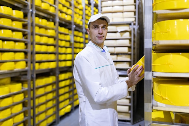 Tecnólogo com queijo nas mãos faz uma inspeção de produção pronta no departamento de fábrica de laticínios