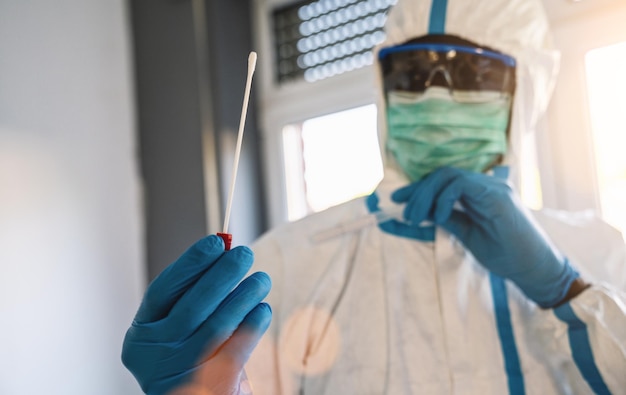 Tecnólogo de saúde médica segurando o kit de coleta de swab COVID19 usando luvas de máscara de proteção de EPI branco tubo de ensaio para coletar amostra de paciente OP NP Processo de protocolo de teste de DNA PCR