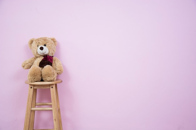 Teddy Bear en una silla de madera con paredes rosas