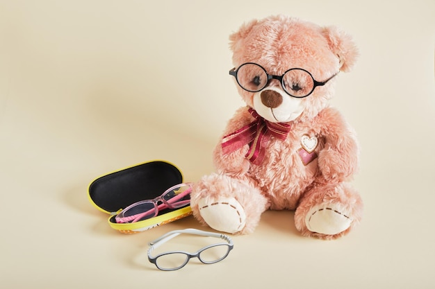 Teddybär mit Brille auf beigem Hintergrund