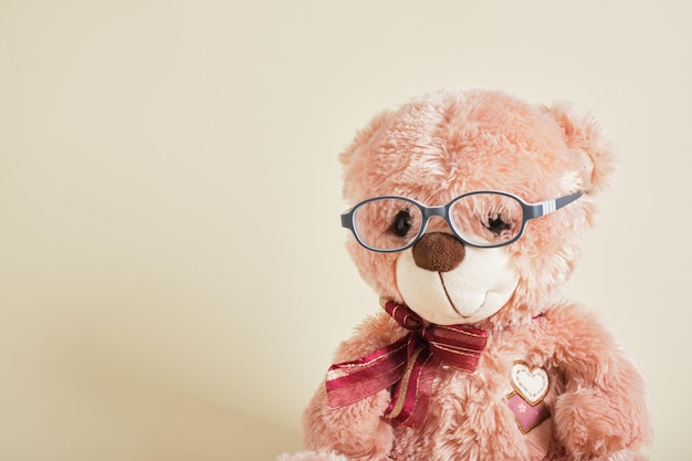 Teddybär mit Brille auf beigem Hintergrund