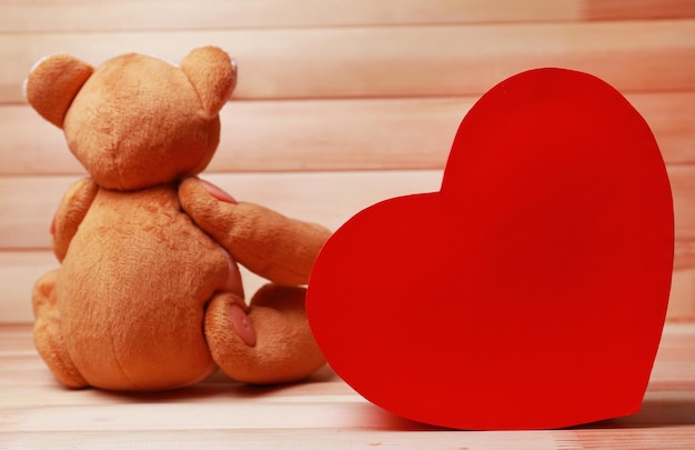 Teddybär mit rotem Herzen auf Holzuntergrund